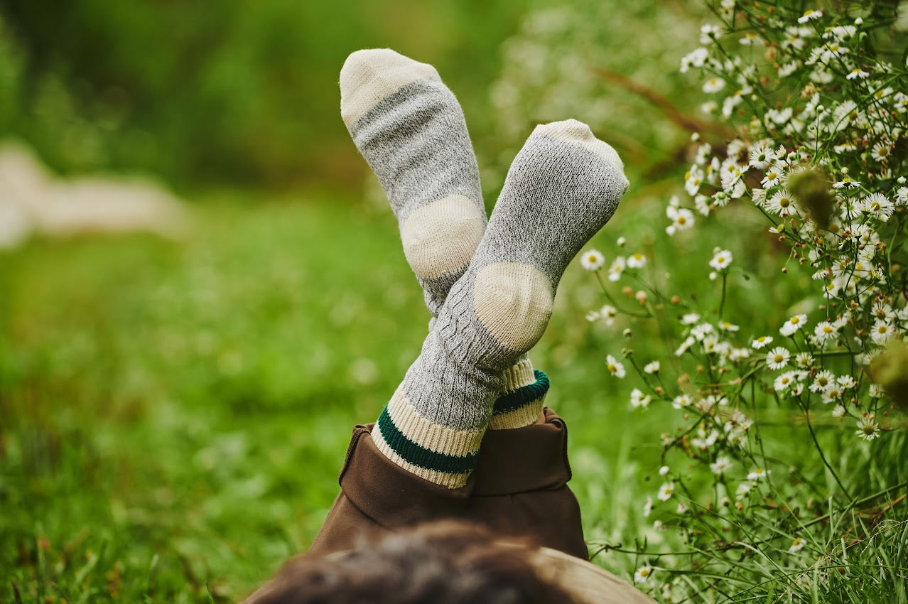 Pieds portant des bas Growers & Co. croisés dans l'herbe