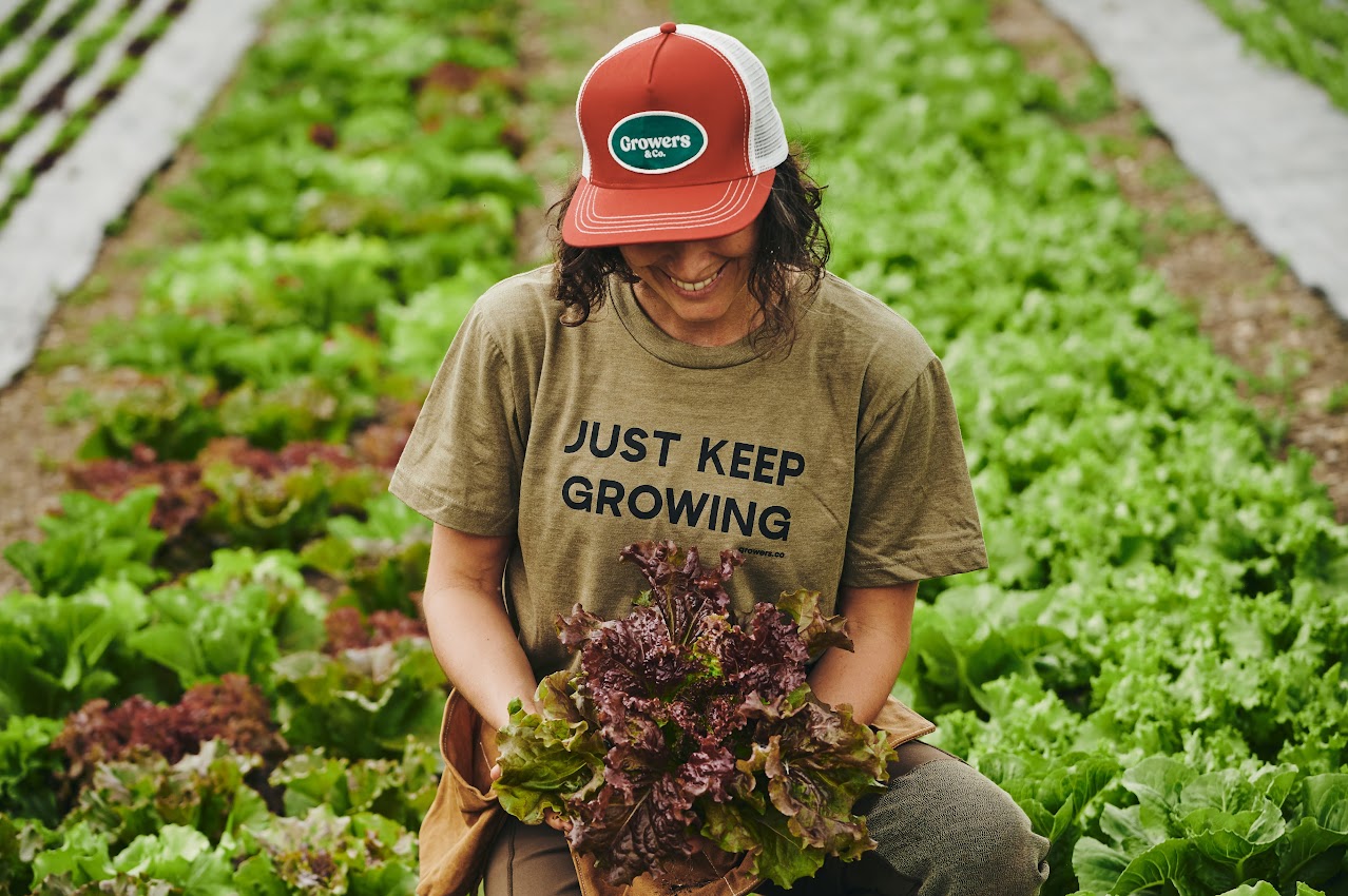 Personne portant la casquette trucker Roma Growers & Co. en extérieur dans un jardin