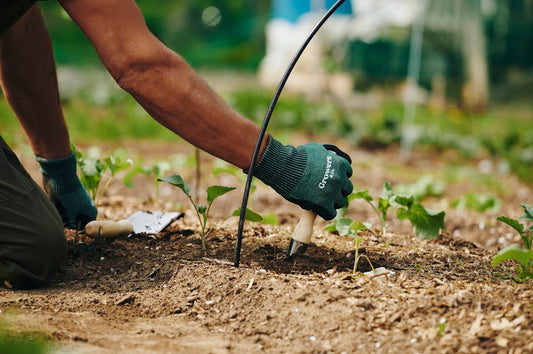 Gants de jardinage Growers & Co. portés par une personne manipulant des outils dans le sol