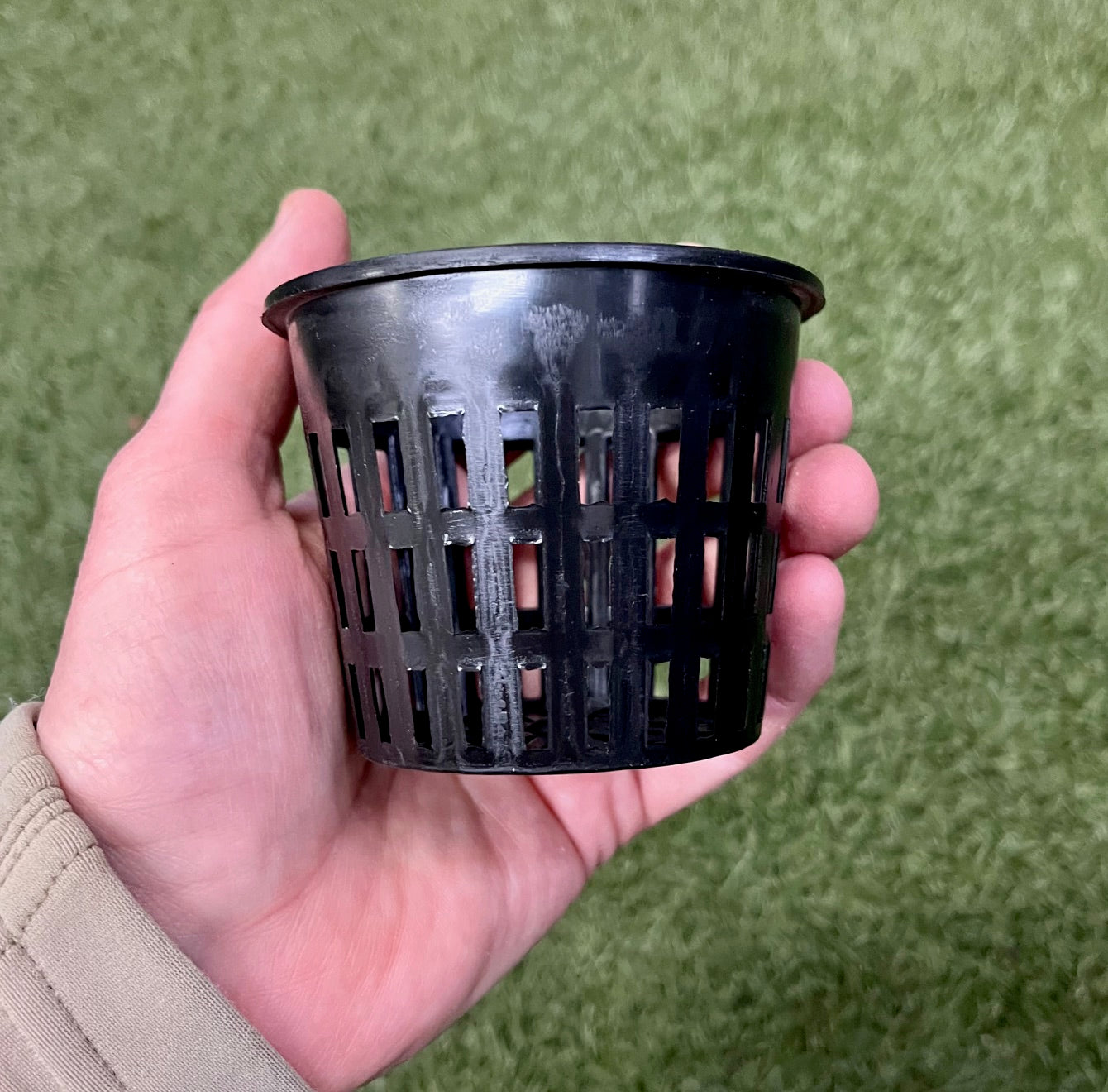 Pot noir ajoure tenu dans une main pour montrer sa taille