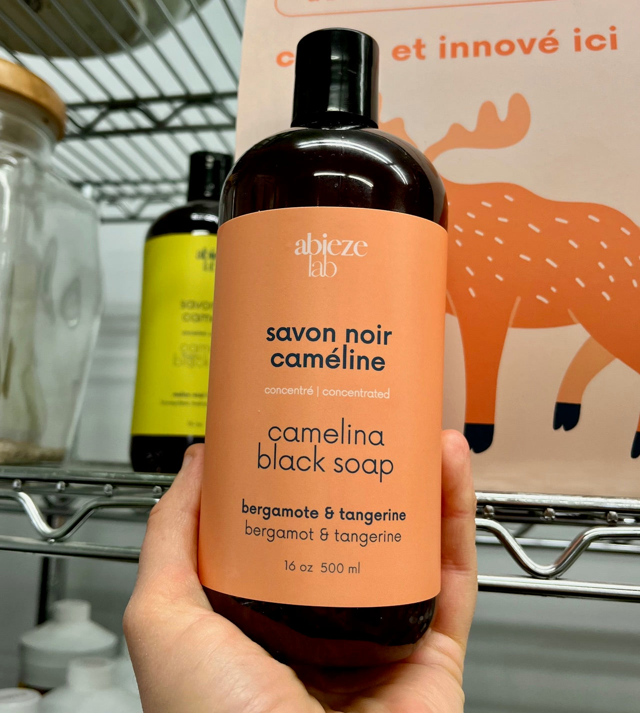 Main tenant une bouteille de savon noir a la cameline Abieze parfum bergamote