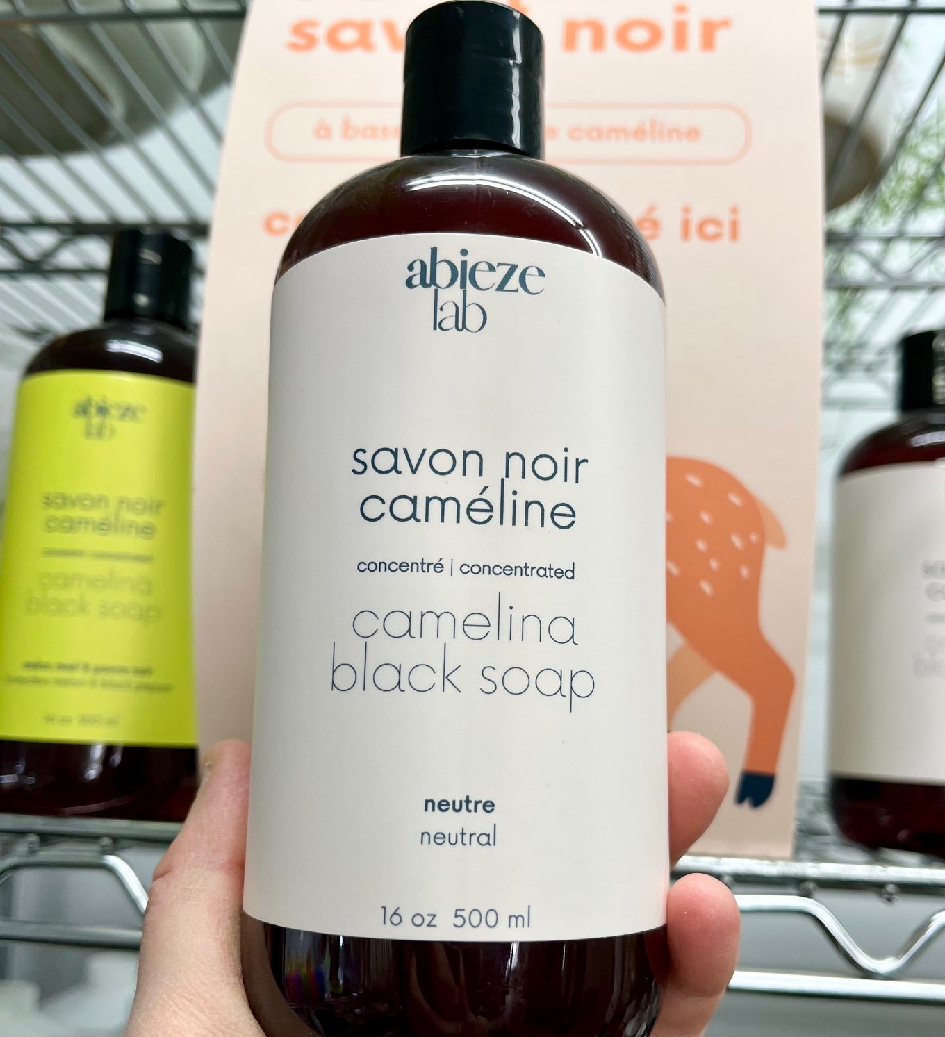 Main tenant une bouteille de savon noir a la cameline Abieze parfum neutre