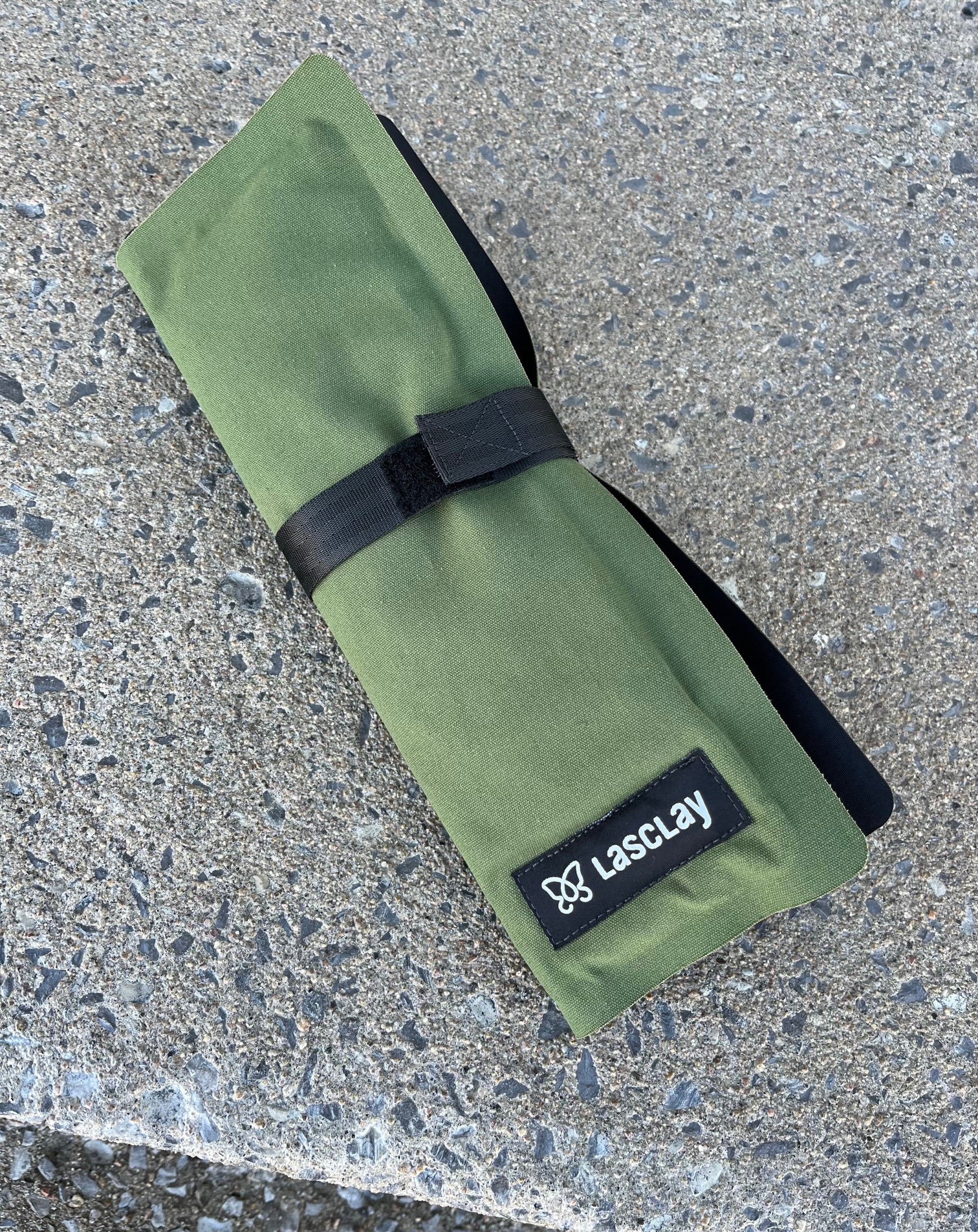Coussin d'assise isotherme en format accordéon plié, maintenu par une ganse à velcro, prêt pour le transport.