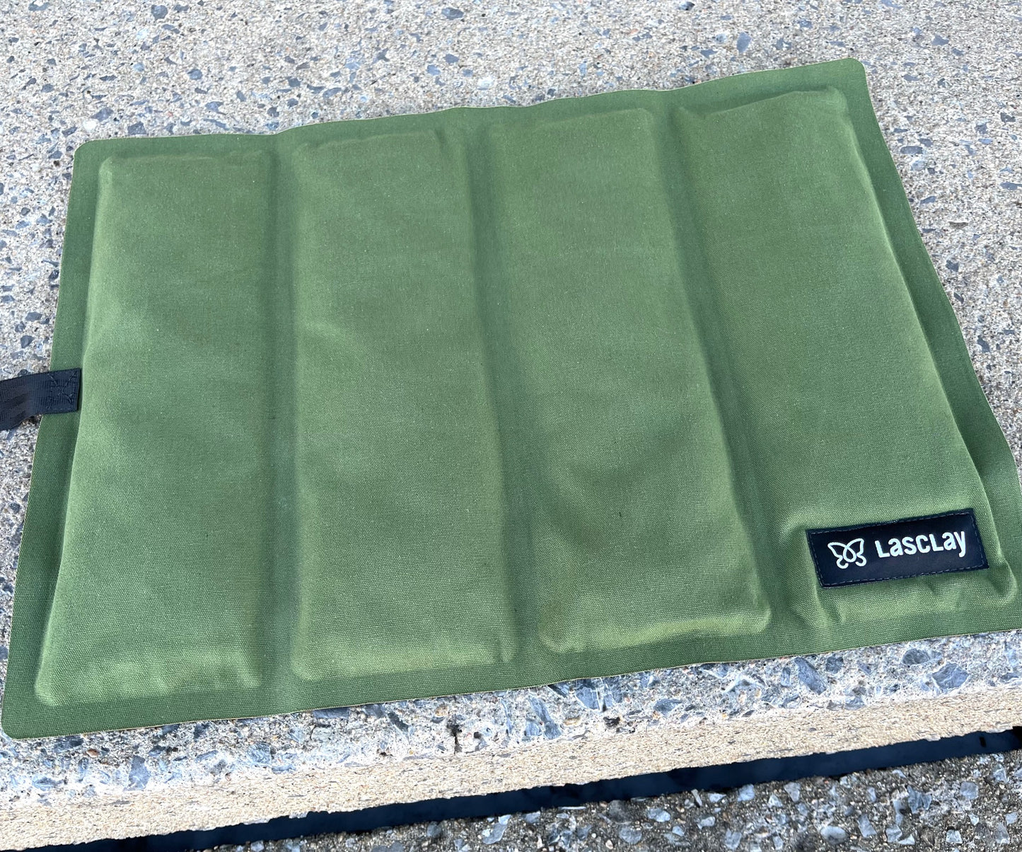 Personne utilisant le coussin isotherme Lasclay en position assise sur une surface extérieure pour rester au chaud et au sec.