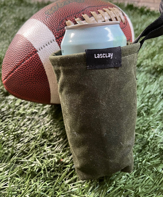Manchon isotherme en asclépiade contenant une canette, posé à côté d'un ballon de football américain sur une pelouse
