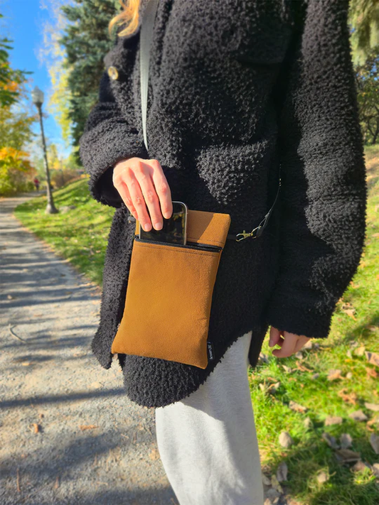 Personne portant la pochette isotherme couleur caramel en bandoulière, contenant un téléphone portable.