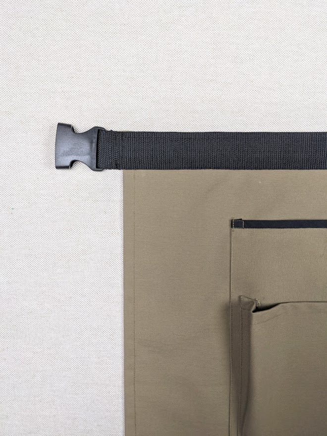 Gros plan sur le système d'attache et la ceinture du tablier de jardinage en coton.